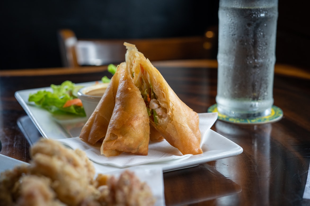 Spring rolls on a plate with sauce and glass of water.